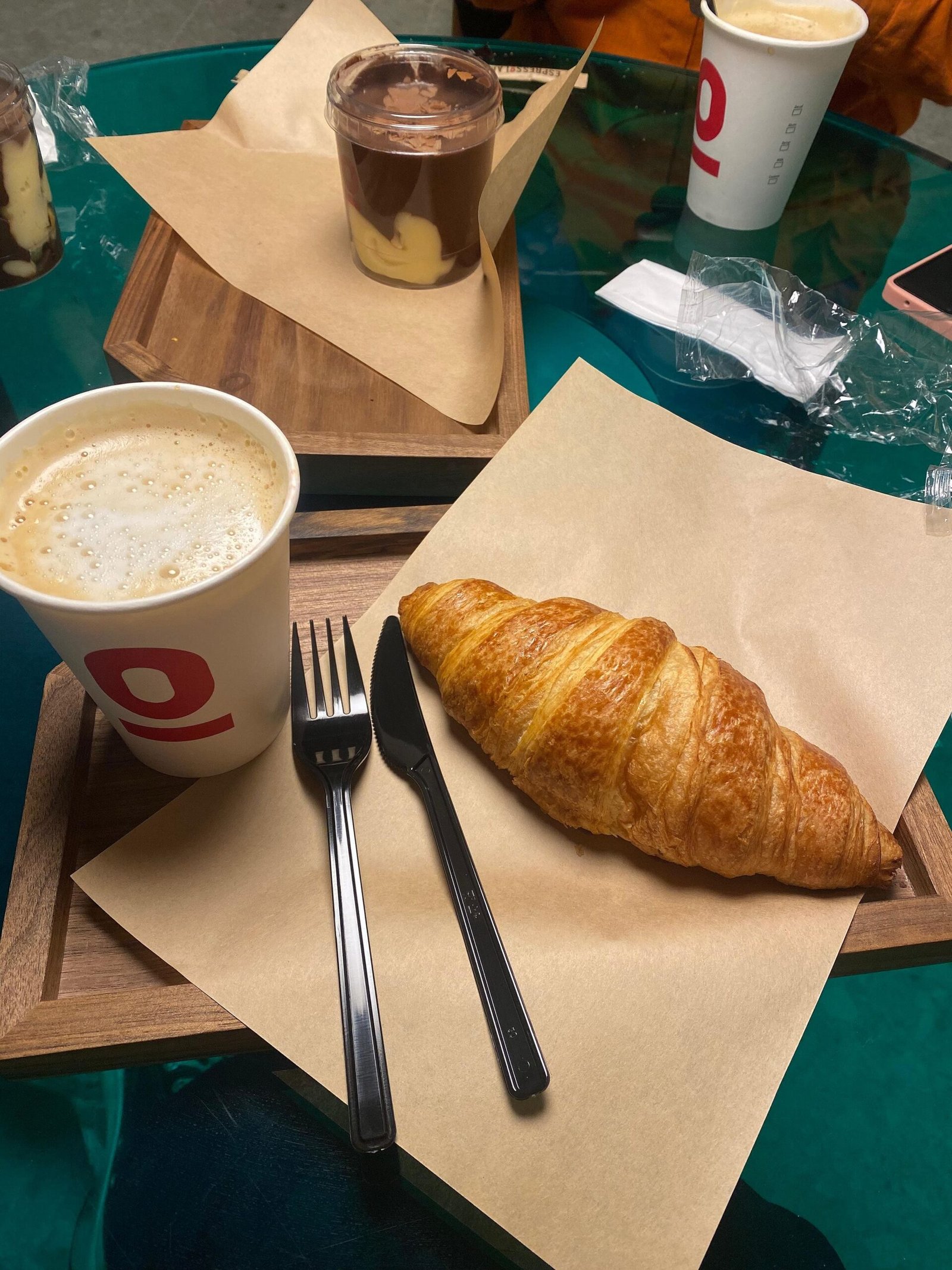 Home A cozy breakfast setting featuring a latte, croissant, and chocolate pudding on a wooden tray.